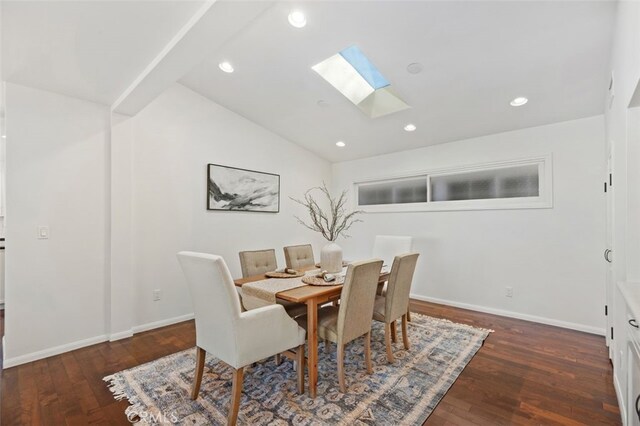 dining room with dark hardwood / wood-style floors and lofted ceiling with skylight