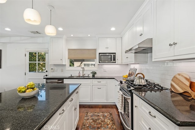 kitchen with stainless steel appliances, white cabinetry, sink, and dark stone countertops