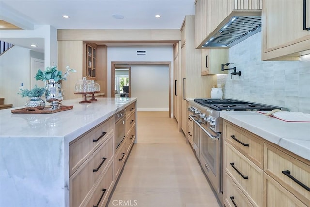 kitchen with custom exhaust hood, light brown cabinets, tasteful backsplash, and high end stainless steel range oven