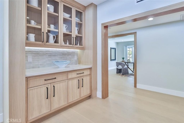 bar featuring light brown cabinetry and backsplash