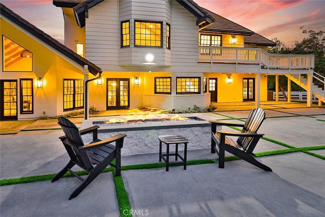 back house at dusk featuring french doors and a patio area