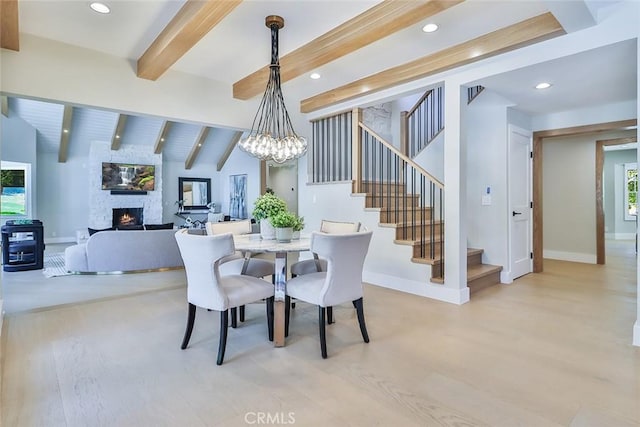 dining area featuring light hardwood / wood-style floors, wooden ceiling, a fireplace, a chandelier, and lofted ceiling with beams