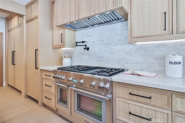 kitchen featuring double oven range, light brown cabinetry, custom exhaust hood, and backsplash