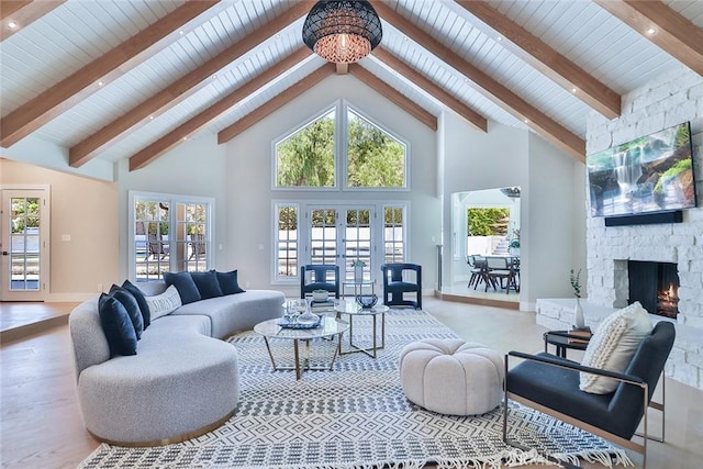 living room with beamed ceiling, french doors, a stone fireplace, and high vaulted ceiling