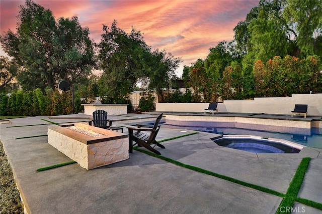 pool at dusk with an in ground hot tub, a fire pit, and a patio