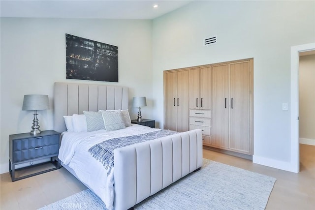 bedroom featuring light hardwood / wood-style flooring and a high ceiling