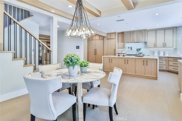 dining area featuring an inviting chandelier, light hardwood / wood-style flooring, and beamed ceiling