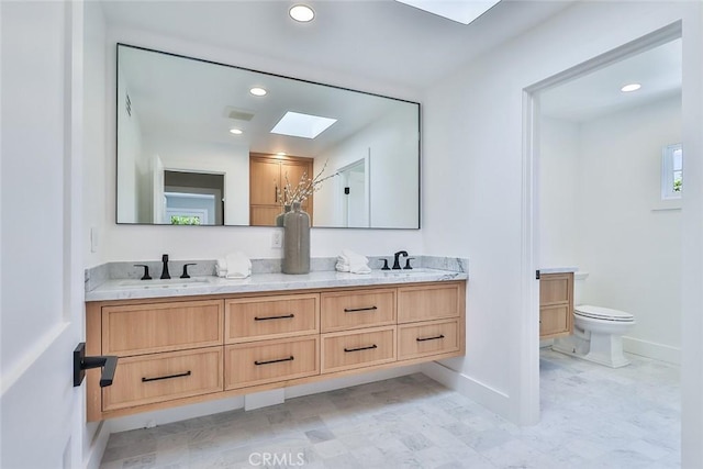 bathroom with toilet, vanity, and a skylight