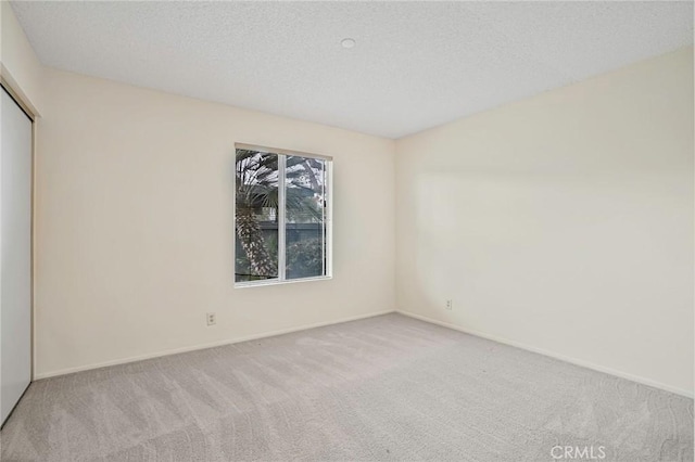 empty room featuring light colored carpet and a textured ceiling