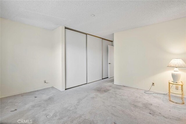 unfurnished room featuring light colored carpet and a textured ceiling