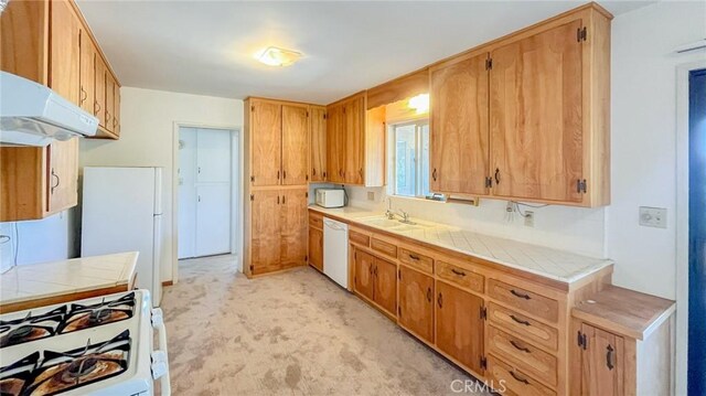 kitchen with tile counters, sink, extractor fan, and white appliances