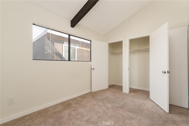 unfurnished bedroom with light carpet, multiple closets, and vaulted ceiling with beams