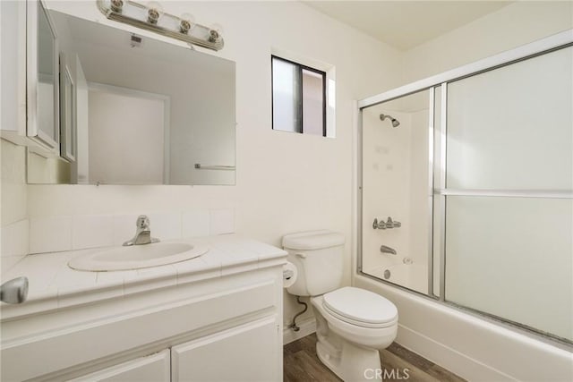 full bathroom featuring toilet, enclosed tub / shower combo, vanity, and hardwood / wood-style floors