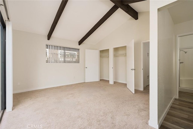 unfurnished bedroom featuring high vaulted ceiling, carpet floors, beam ceiling, and multiple closets