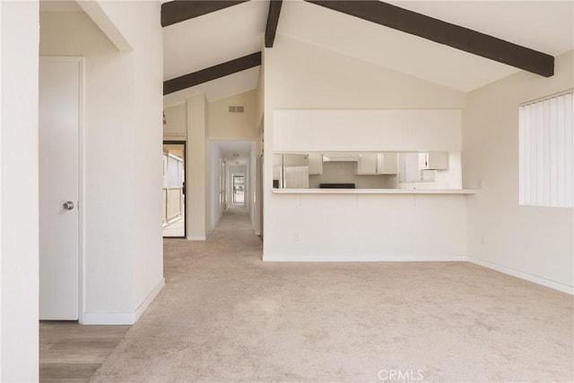 unfurnished living room featuring light carpet and vaulted ceiling with beams