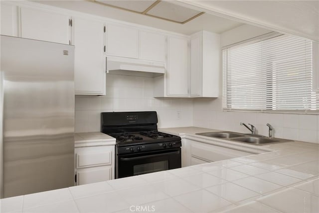 kitchen featuring tile countertops, white cabinetry, stainless steel refrigerator, black range with gas stovetop, and sink