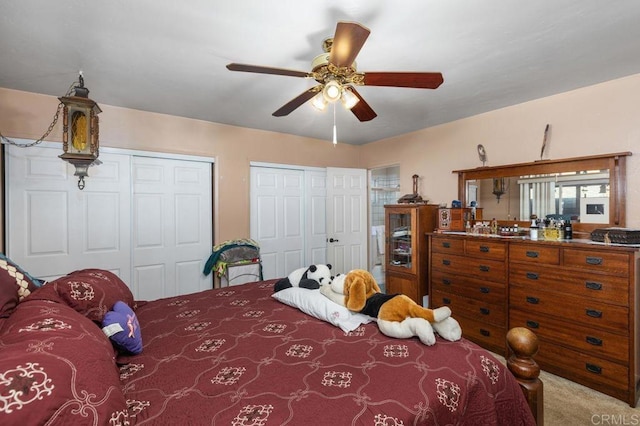 bedroom featuring ceiling fan, two closets, and carpet flooring