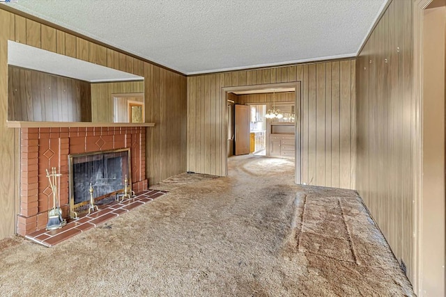 unfurnished living room with a tile fireplace, wooden walls, a textured ceiling, and dark colored carpet