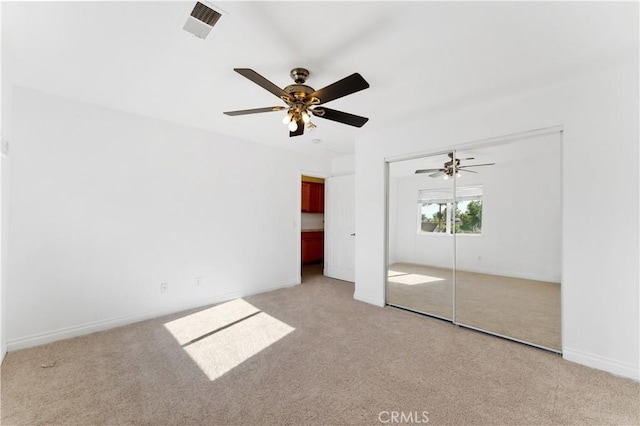 unfurnished bedroom featuring light carpet, ceiling fan, visible vents, and baseboards