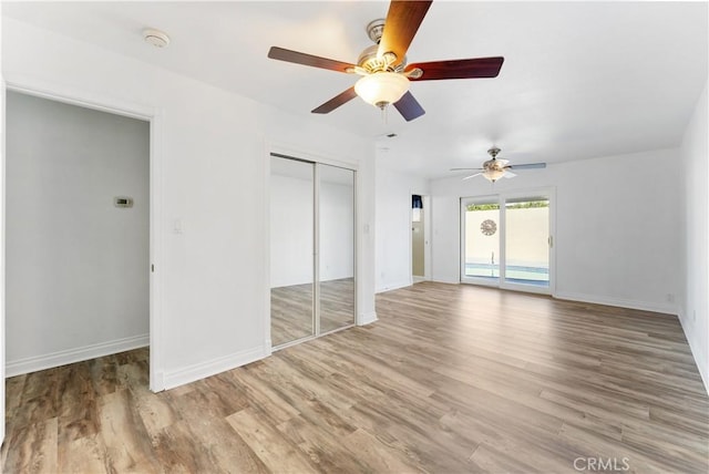 unfurnished bedroom featuring access to outside, a closet, light wood-type flooring, and baseboards