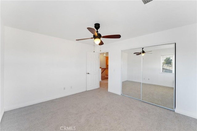 unfurnished bedroom with a closet, light carpet, ceiling fan, and baseboards