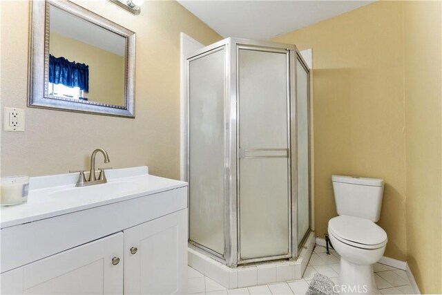 full bathroom with tile patterned flooring, a shower stall, vanity, and toilet