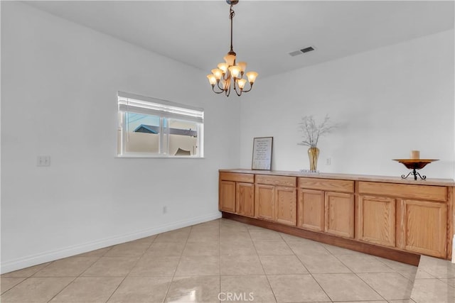 unfurnished dining area with a chandelier, visible vents, baseboards, and light tile patterned floors