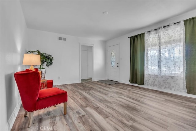 sitting room with light wood-type flooring, visible vents, and baseboards