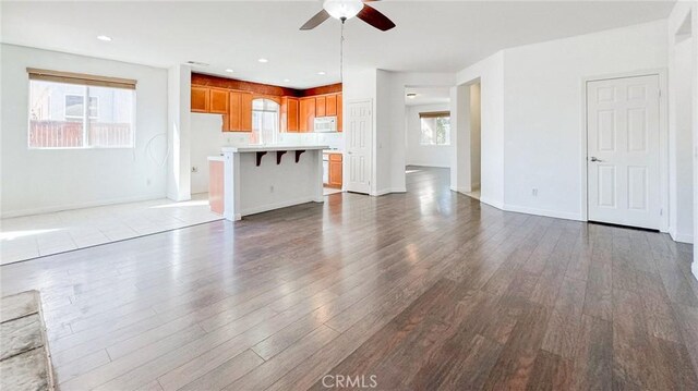 unfurnished living room with hardwood / wood-style flooring, ceiling fan, and plenty of natural light