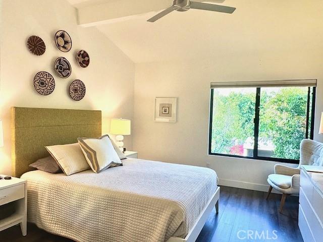 bedroom featuring ceiling fan, dark hardwood / wood-style flooring, and beamed ceiling