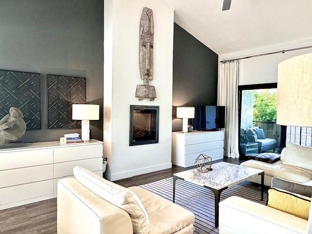 living room with ceiling fan, vaulted ceiling, and dark hardwood / wood-style flooring