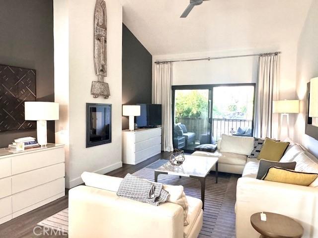 living room with ceiling fan, dark wood-type flooring, and lofted ceiling