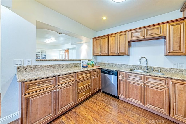 kitchen with dishwasher, sink, light stone counters, and light hardwood / wood-style floors