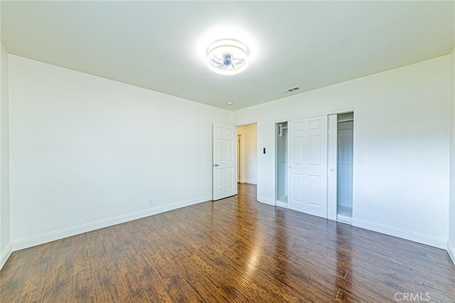 unfurnished bedroom with dark wood-type flooring and a closet