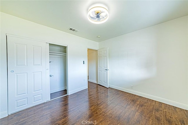 unfurnished bedroom featuring dark wood-type flooring and a closet