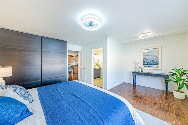 bedroom featuring dark wood-type flooring, crown molding, and connected bathroom