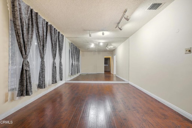 unfurnished room with hardwood / wood-style floors, a textured ceiling, and track lighting