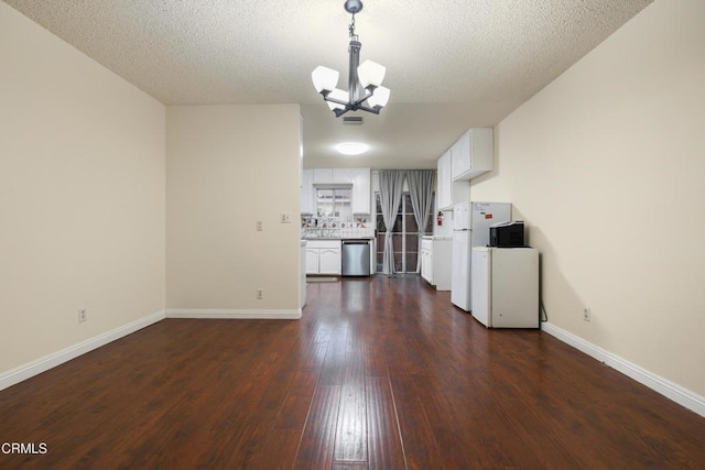 unfurnished living room featuring a textured ceiling, dark hardwood / wood-style floors, and a notable chandelier