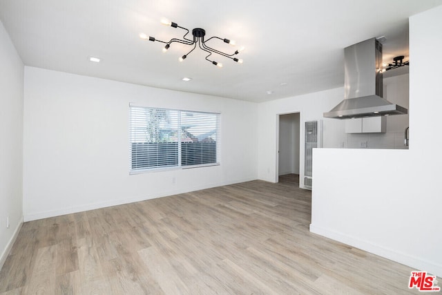 unfurnished living room featuring light wood-type flooring and an inviting chandelier