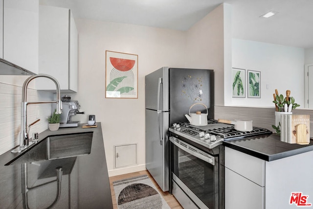 kitchen featuring tasteful backsplash, light hardwood / wood-style floors, sink, white cabinets, and gas range