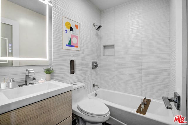 full bathroom with toilet, tiled shower / bath combo, decorative backsplash, tile walls, and vanity