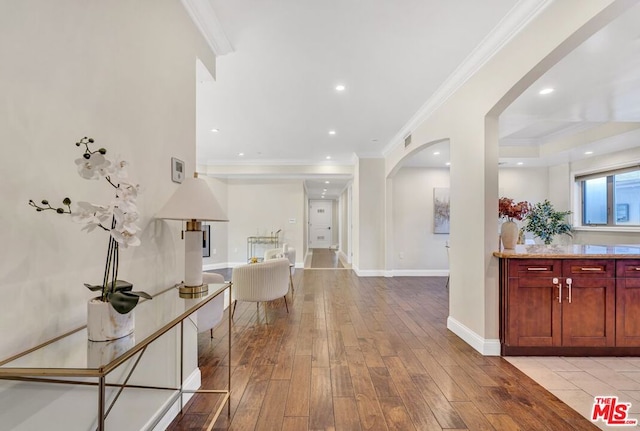 corridor with light hardwood / wood-style floors and ornamental molding