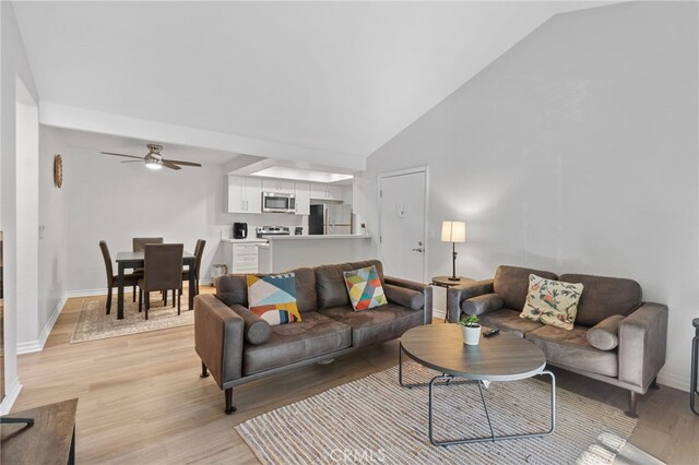 living room featuring ceiling fan, high vaulted ceiling, and light hardwood / wood-style flooring