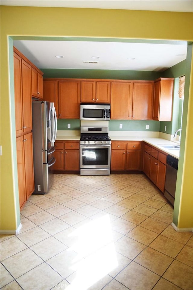 kitchen with appliances with stainless steel finishes, light tile patterned flooring, and sink