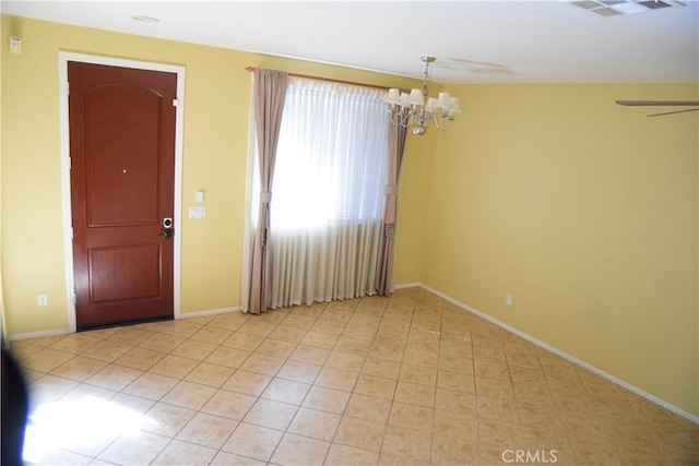 spare room featuring ceiling fan with notable chandelier