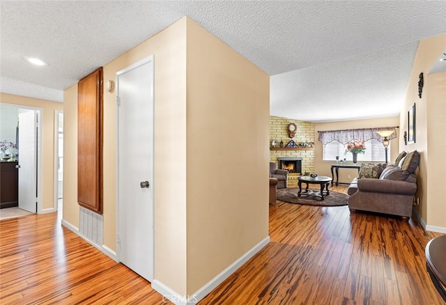 hallway with a textured ceiling and wood-type flooring