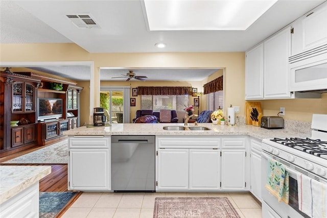 kitchen with white cabinetry, sink, white appliances, and kitchen peninsula