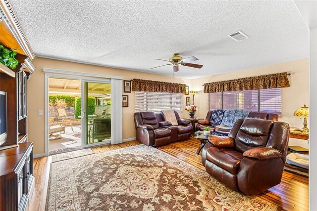 living room featuring ceiling fan, a textured ceiling, and light hardwood / wood-style flooring