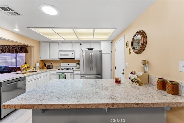 kitchen with white cabinets, stainless steel appliances, sink, kitchen peninsula, and a breakfast bar area