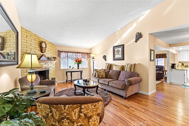 living room with a textured ceiling, light wood-type flooring, and a fireplace